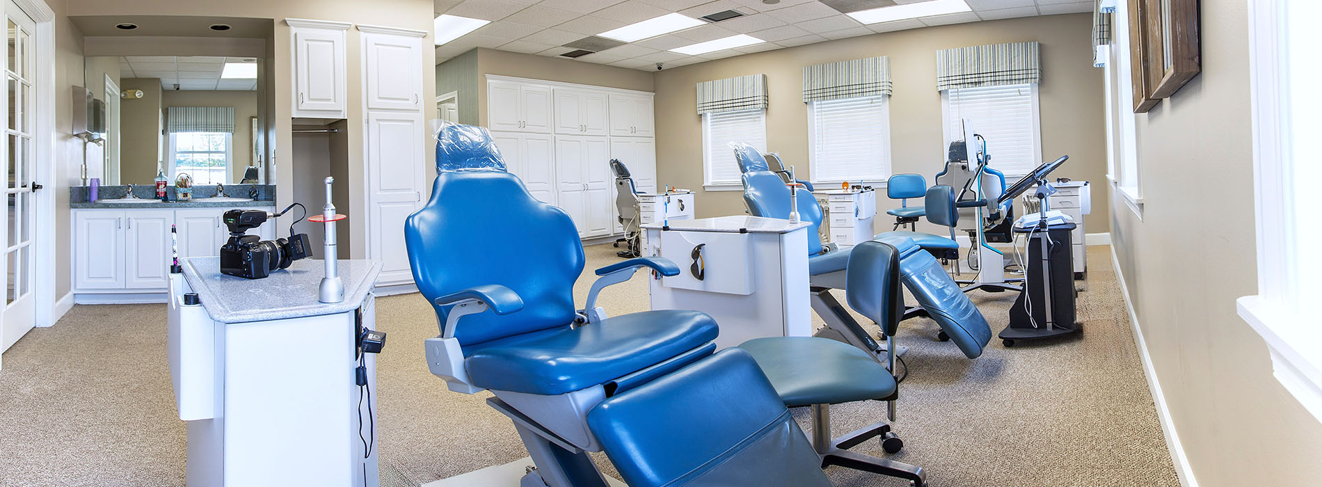 The image shows an interior space that appears to be a dental office with chairs, equipment, and a reception area.